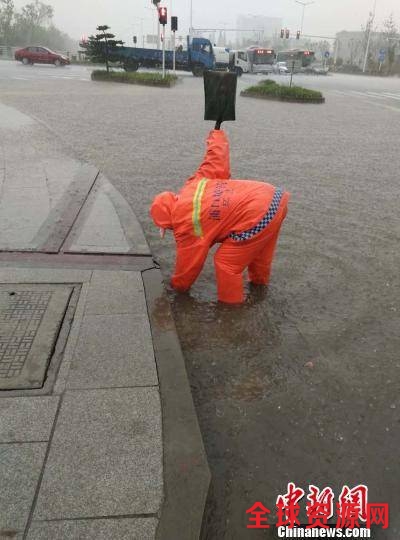 环卫工人在雨中忙着去除排水口里的落叶和堵塞物。 城管供图