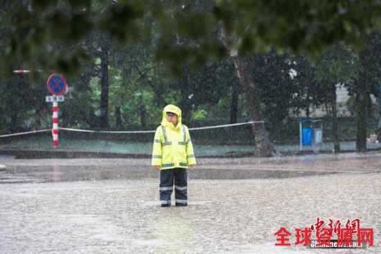 资料图：6月13日，浙江省金华市浦江县大雨倾盆，交警冒雨执勤，阻拦车辆进入漫水路段。 中新社发 张浩钺 摄