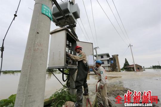 资料图：为配合武警水电部队抗洪抢险，电力人员断开电缆连接。 袁静 摄