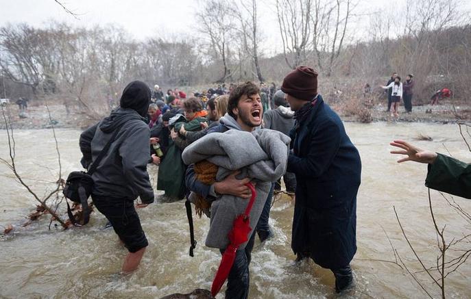 全球:千难民组人链渡河 已有3人淹死